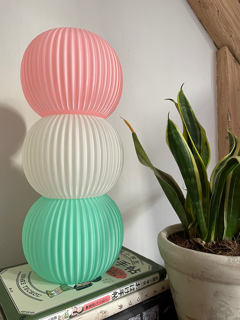 3D printed pink, white and green Dango desk lamp on top of a stack of books