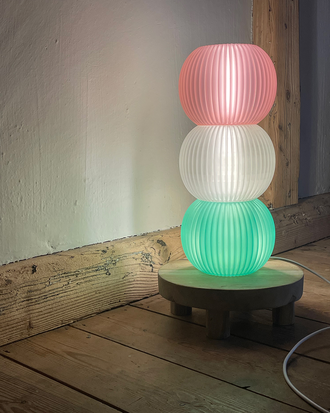 3D printed pink, whitr and green Dango lamp on a wooden stand